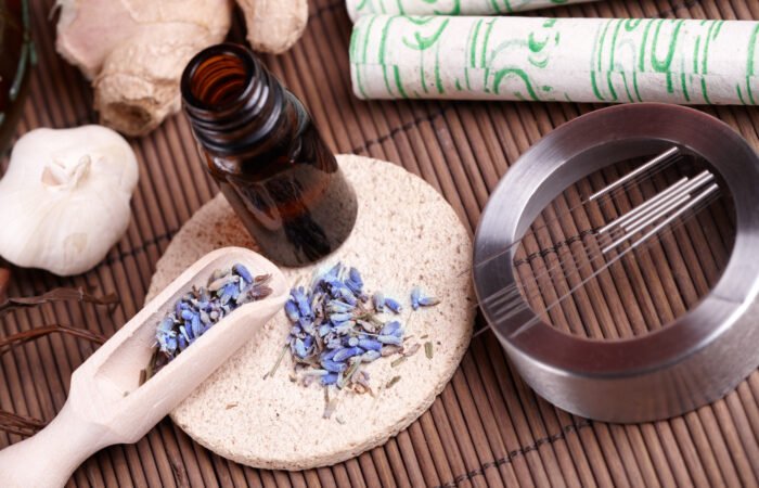 Acupuncture needles and TCM herbs arranged on a table, representing natural hormone-balancing therapies